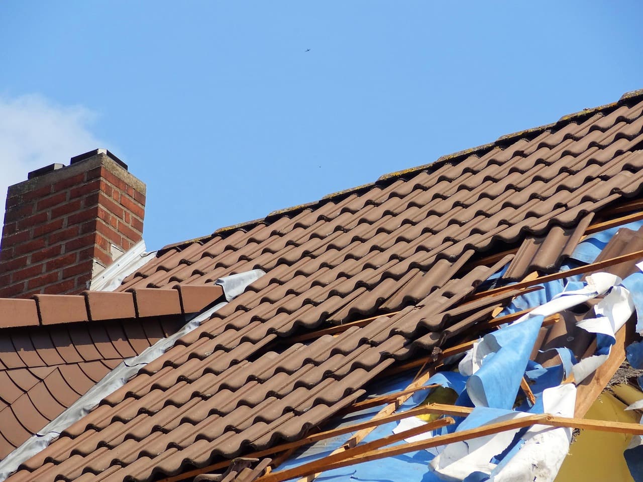 Roof with tiles torn away and timbers exposed after a storm